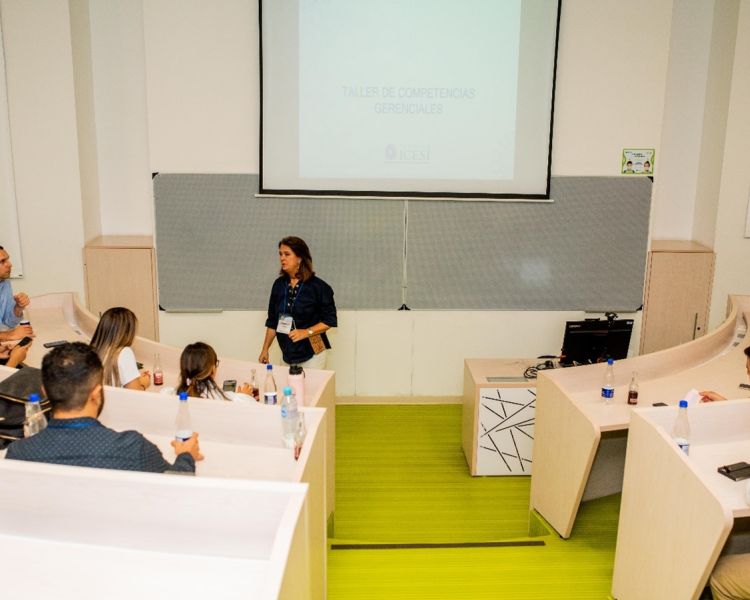Profesora hablando en sala con estudiantes. Vista hacia abajo